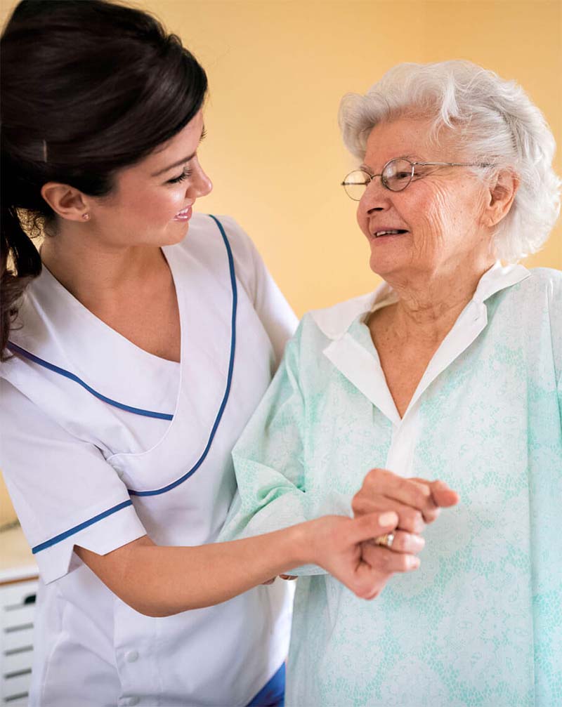 Nurse helping elderly lady to stand up and walk at her house